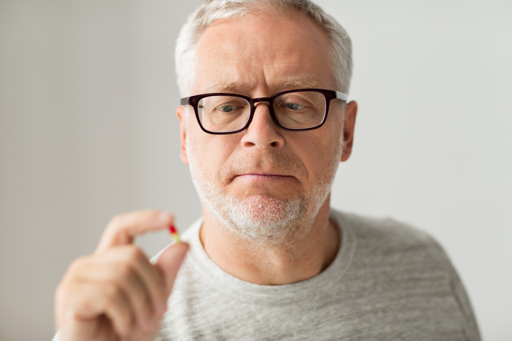 elder guy holding sex enhancement supplement