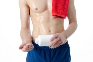 shirtless guy taking enhancement supplement