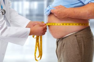 overweight man measures waist circumference