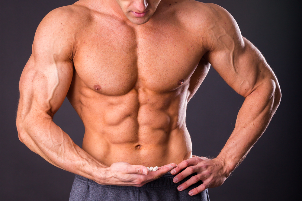 muscular guy holds male enhancement supplements