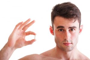 man holds sex enhancement supplement capsule
