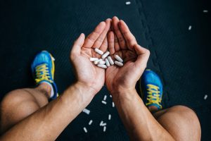 man in gym with enhancement supplement capsules