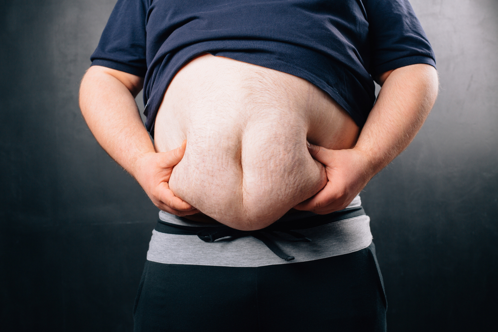 obese man squeezing belly fat