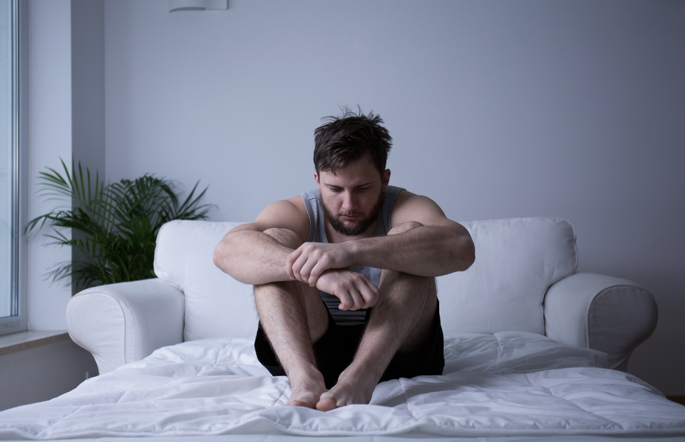 depressed man sitting on bed