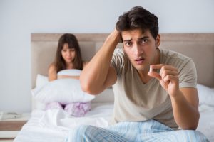 man holding up pill having troubles in the bedroom