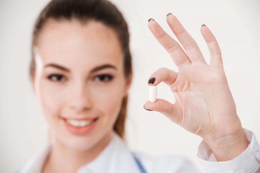 female doctor holding out a capsule