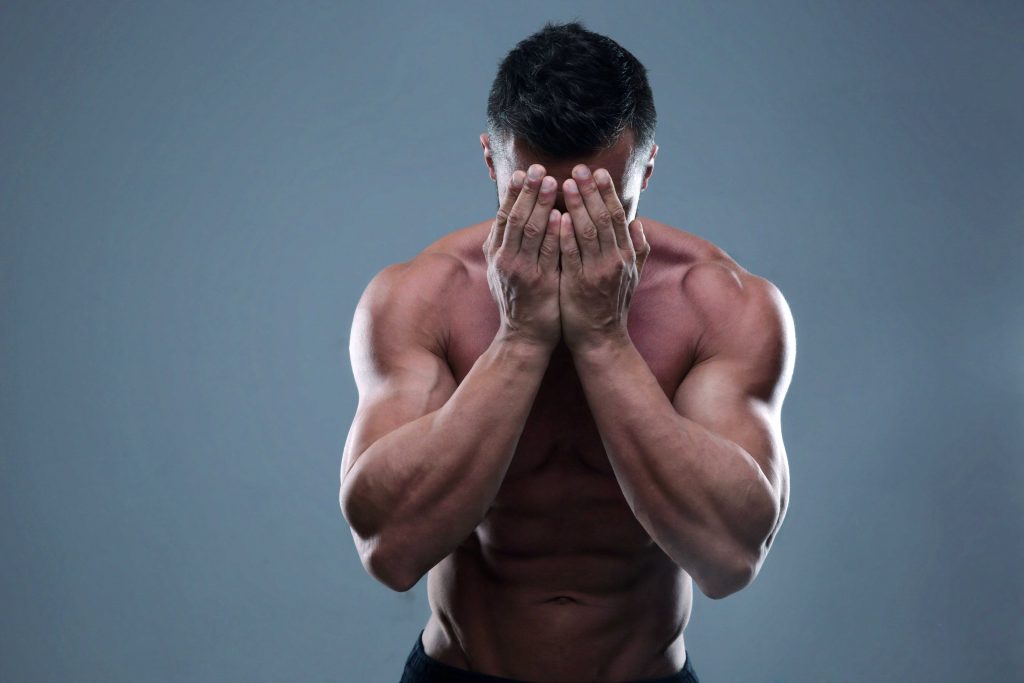 ripped guy burying face in hands