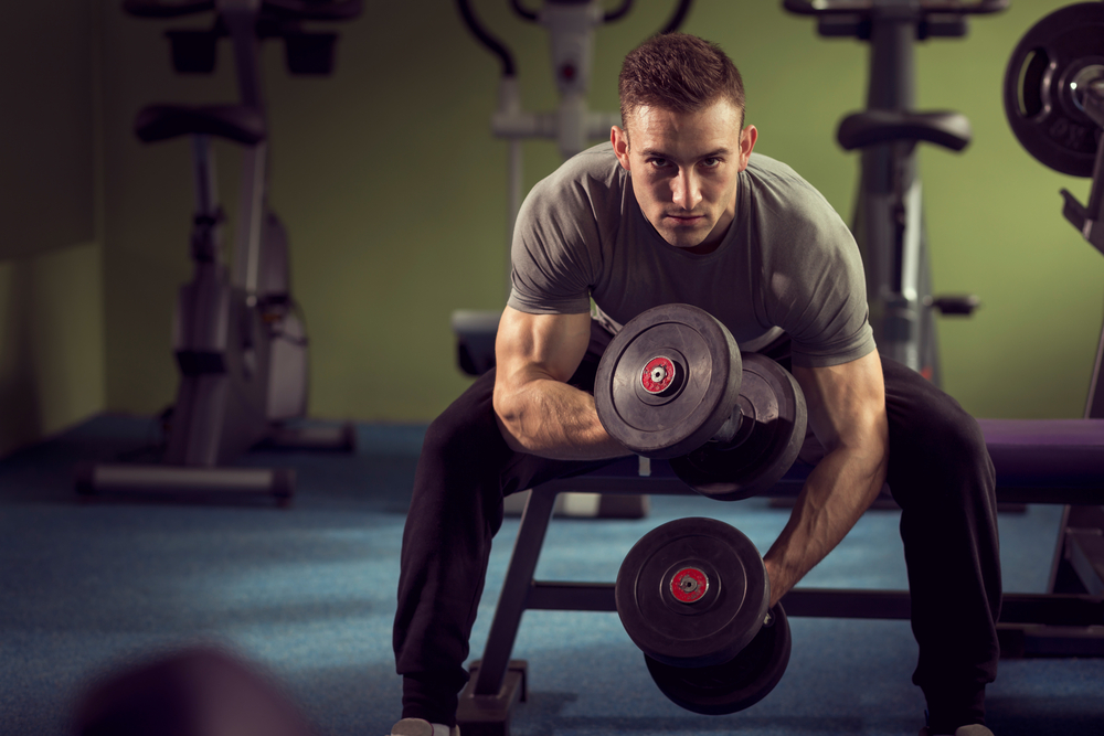 muscular guy in gym lift free weights