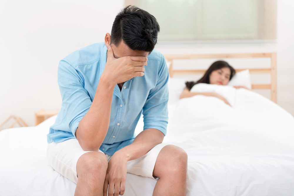 depressed man on edge of bed