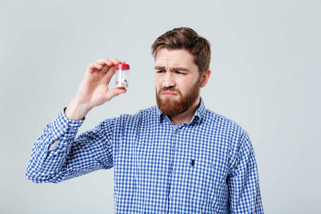 confused man looking at pills bottle